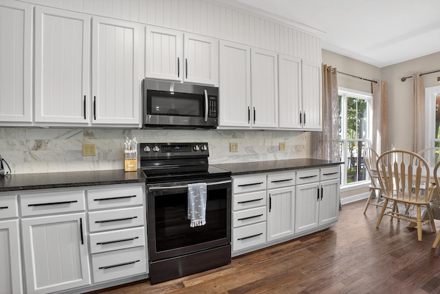 1005 Dennis St, Eatonton, GA 31024 - kitchen featuring stainless steel microwave, electric range, dark wood finished floors, backsplash, and dark stone counters