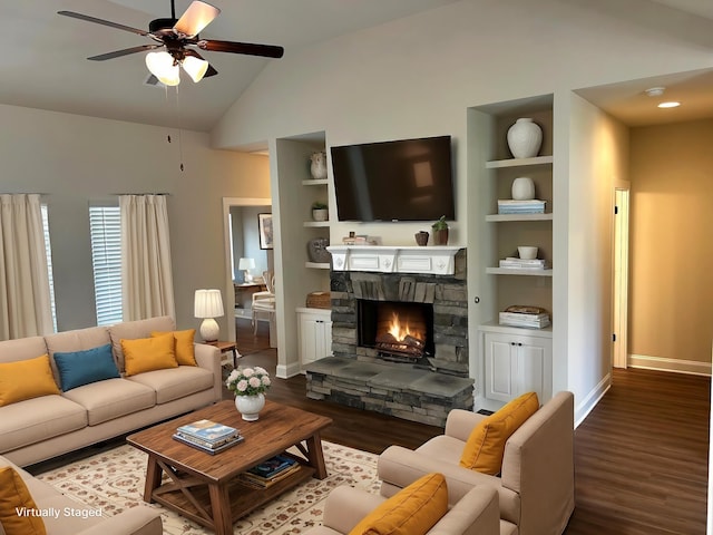 living area with built in features, lofted ceiling, a stone fireplace, wood finished floors, and baseboards