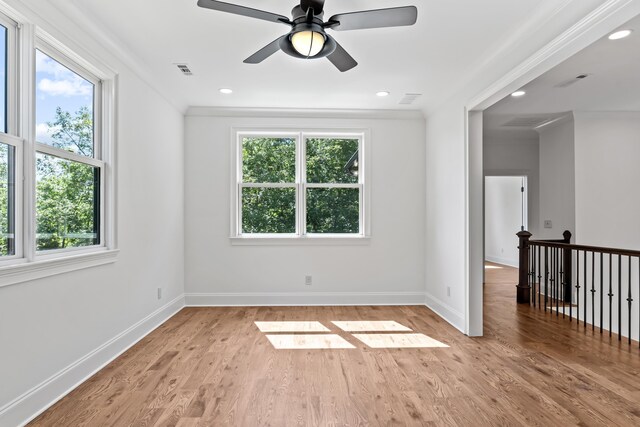 spare room featuring crown molding, a healthy amount of sunlight, and light wood-type flooring