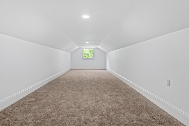 additional living space featuring vaulted ceiling and carpet