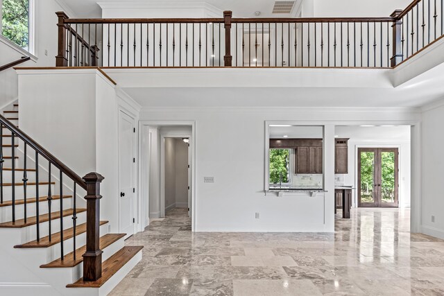 foyer featuring a high ceiling, crown molding, and french doors