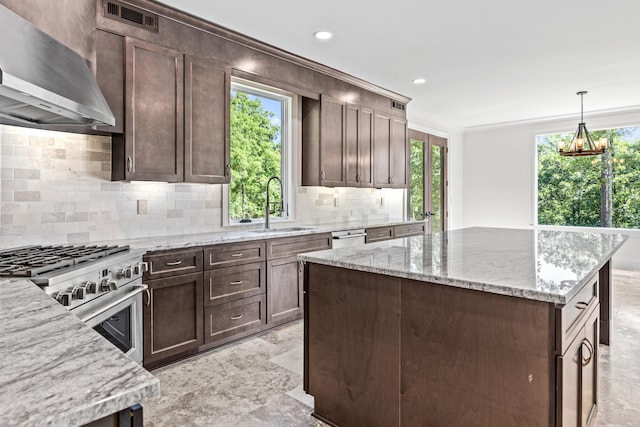 kitchen featuring light stone counters, sink, stainless steel appliances, and wall chimney exhaust hood