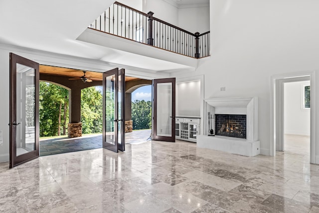 unfurnished living room with an outdoor fireplace, french doors, and a healthy amount of sunlight