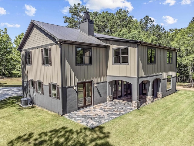 rear view of house with cooling unit, a patio area, and a lawn