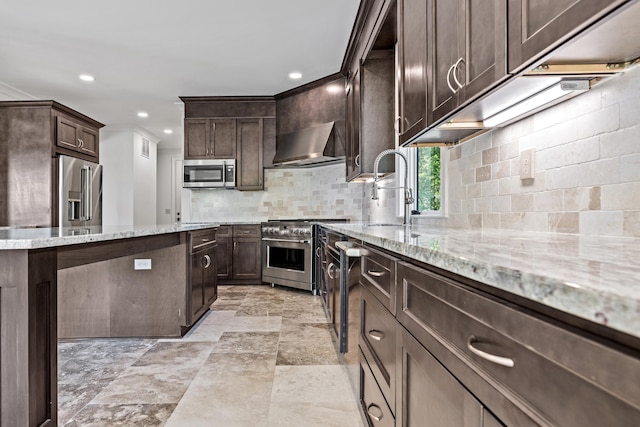 kitchen featuring dark brown cabinetry, high quality appliances, sink, and wall chimney range hood