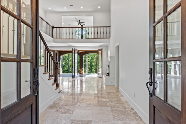 foyer with crown molding, french doors, ceiling fan, and a towering ceiling