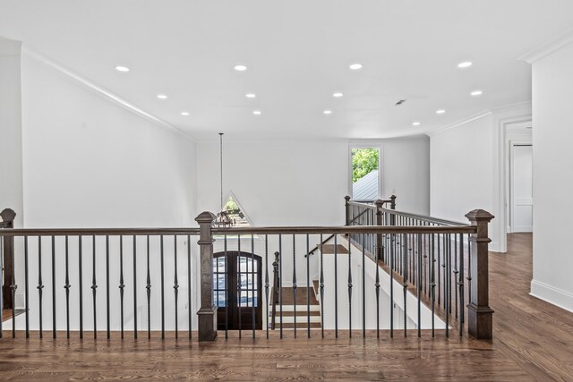 corridor featuring crown molding, dark hardwood / wood-style floors, and a notable chandelier