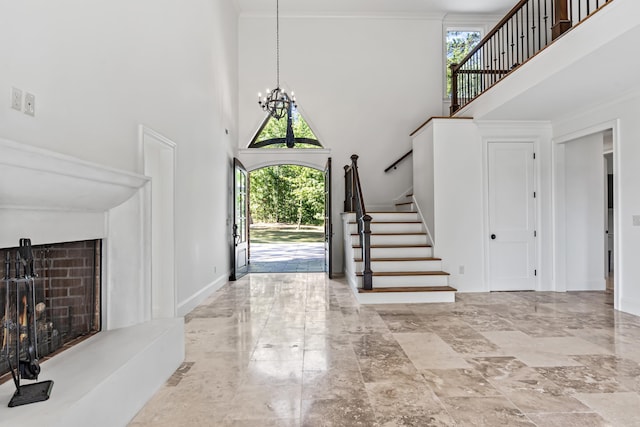 foyer entrance featuring a high ceiling, crown molding, a healthy amount of sunlight, and a notable chandelier