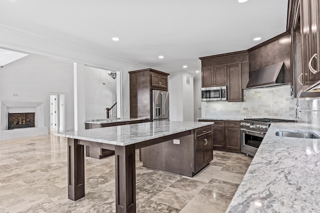 kitchen featuring wall chimney exhaust hood, light stone counters, dark brown cabinets, high quality appliances, and decorative backsplash