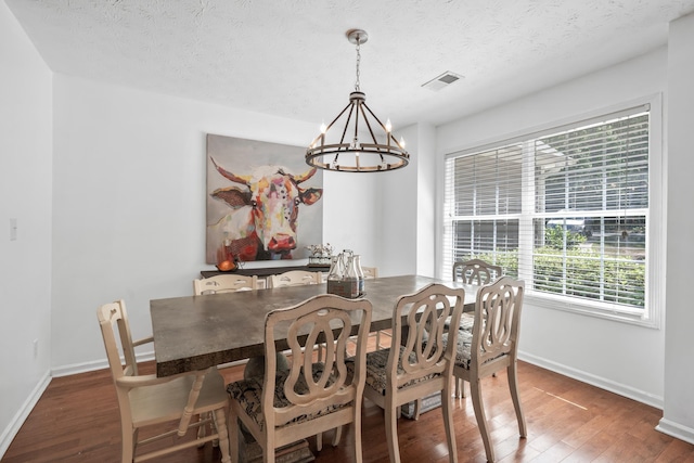 dining area with dark hardwood / wood-style floors, a textured ceiling, and an inviting chandelier