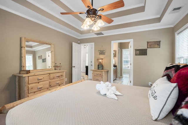 bedroom with crown molding, ceiling fan, ensuite bathroom, and a tray ceiling