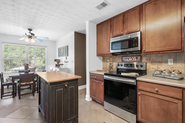 kitchen with tasteful backsplash, light tile patterned floors, a kitchen island, and appliances with stainless steel finishes