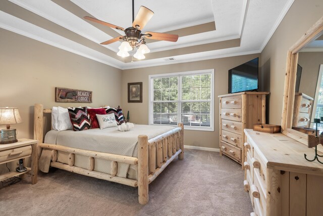 bedroom featuring a raised ceiling, ornamental molding, light colored carpet, and ceiling fan