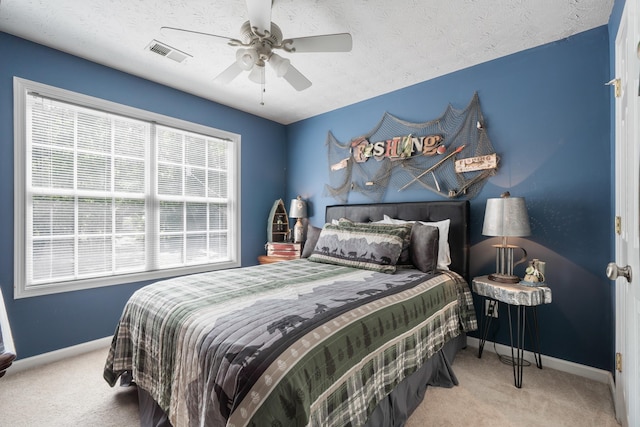 bedroom featuring ceiling fan, light colored carpet, and a textured ceiling