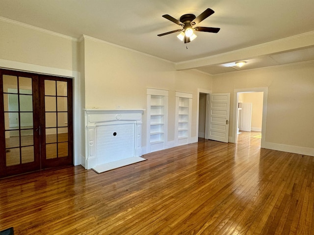 unfurnished living room with crown molding, ceiling fan, built in shelves, and hardwood / wood-style floors