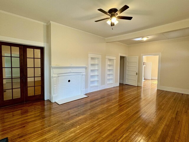 unfurnished living room with crown molding, ceiling fan, built in shelves, and hardwood / wood-style floors