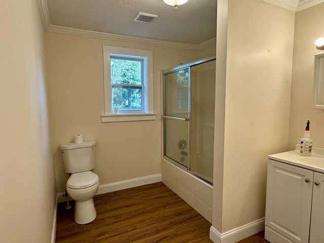 full bathroom featuring bath / shower combo with glass door, hardwood / wood-style flooring, ornamental molding, vanity, and toilet