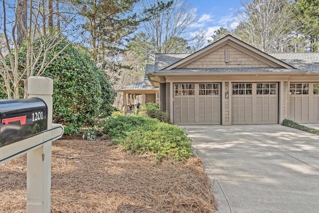 exterior space with a shingled roof, driveway, and an attached garage