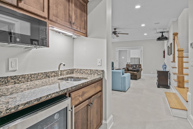 kitchen with stone countertops, light colored carpet, wine cooler, black microwave, and a sink