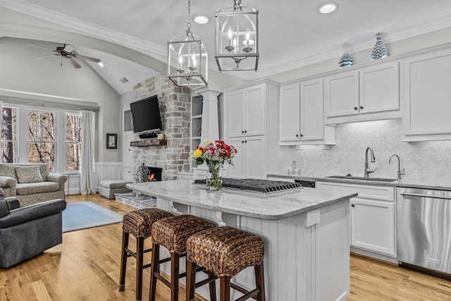 kitchen with a kitchen island, appliances with stainless steel finishes, open floor plan, a stone fireplace, and a sink