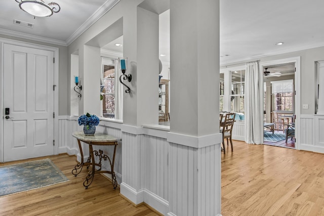 entrance foyer featuring crown molding, visible vents, and wood finished floors