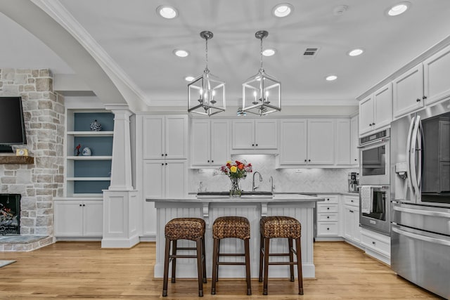 kitchen with visible vents, white cabinets, appliances with stainless steel finishes, crown molding, and a fireplace