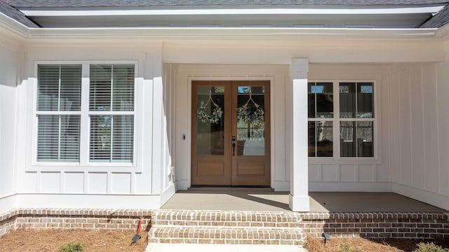 doorway to property with french doors, a shingled roof, board and batten siding, and a porch