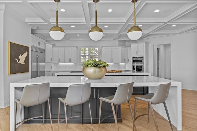 kitchen with a large island, light stone countertops, appliances with stainless steel finishes, white cabinets, and pendant lighting