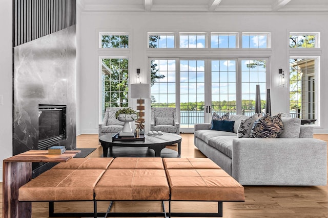 living room featuring hardwood / wood-style floors, crown molding, beamed ceiling, and plenty of natural light