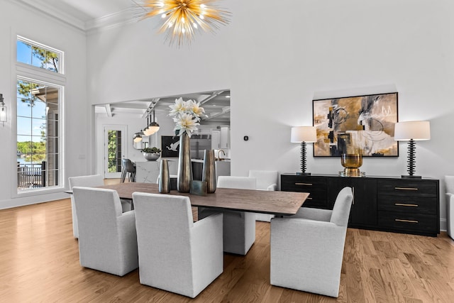 dining space featuring a towering ceiling, hardwood / wood-style flooring, crown molding, and a chandelier