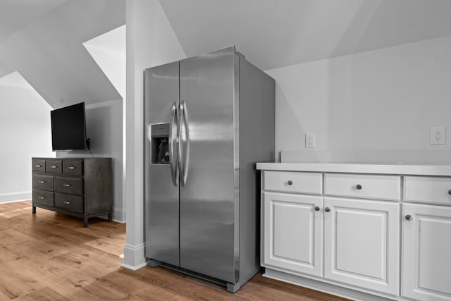 kitchen featuring lofted ceiling, white cabinets, stainless steel fridge, and light hardwood / wood-style flooring