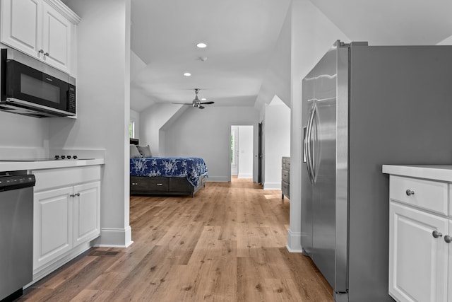 interior space with light wood-type flooring, lofted ceiling, ceiling fan, appliances with stainless steel finishes, and white cabinets