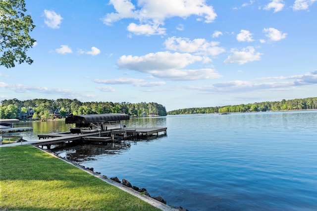 view of dock with a lawn and a water view