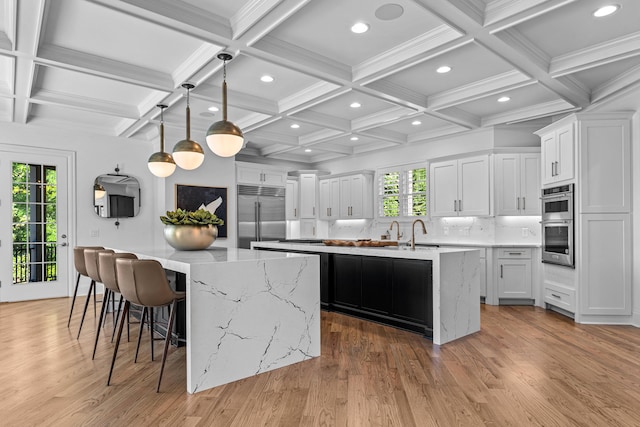 kitchen with white cabinets, an island with sink, a wealth of natural light, and stainless steel appliances