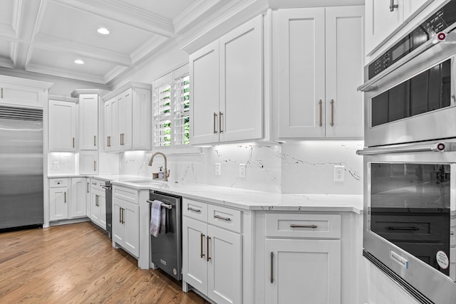 kitchen with sink, white cabinetry, crown molding, stainless steel appliances, and light stone countertops