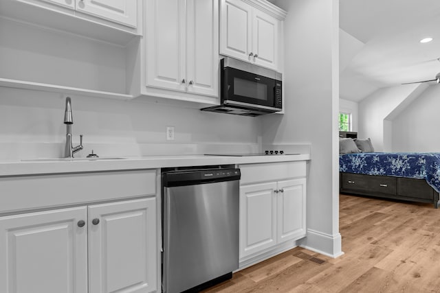 kitchen with vaulted ceiling, sink, light wood-type flooring, white cabinetry, and stainless steel appliances