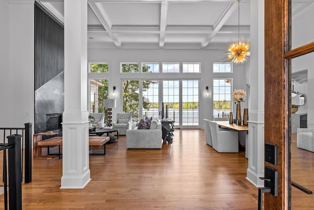 interior space with coffered ceiling, an inviting chandelier, wood-type flooring, beamed ceiling, and ornate columns