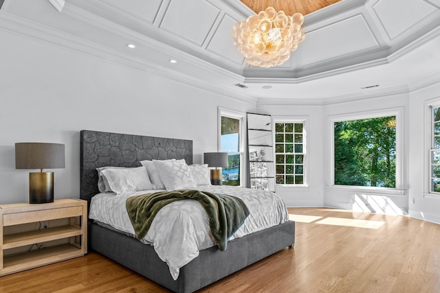 bedroom featuring coffered ceiling, ornamental molding, a notable chandelier, and light hardwood / wood-style floors