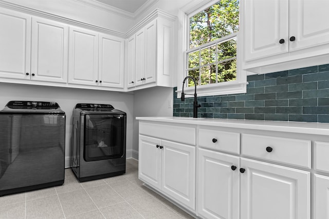 washroom featuring light tile patterned flooring, independent washer and dryer, crown molding, sink, and cabinets