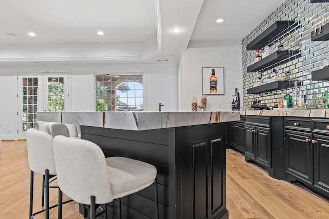 bar featuring a raised ceiling, light hardwood / wood-style flooring, and ornamental molding