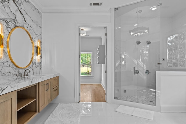 bathroom with crown molding, vanity, and a shower with door