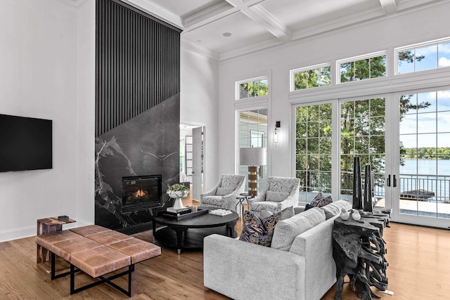 living room featuring coffered ceiling, wood-type flooring, a water view, ornamental molding, and beam ceiling