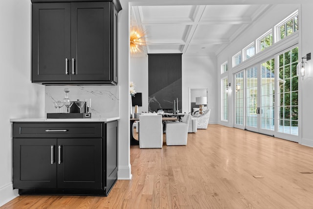 bar featuring light wood-type flooring, coffered ceiling, beamed ceiling, and backsplash