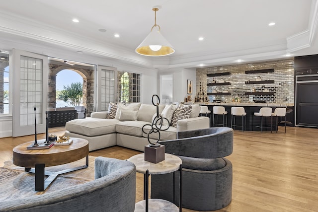 living room featuring crown molding, light hardwood / wood-style floors, and a raised ceiling