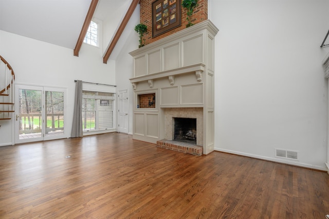 unfurnished living room with high vaulted ceiling, a fireplace, visible vents, stairway, and beamed ceiling