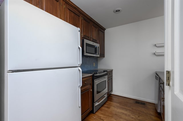 kitchen with dark wood-style floors, visible vents, light countertops, backsplash, and appliances with stainless steel finishes