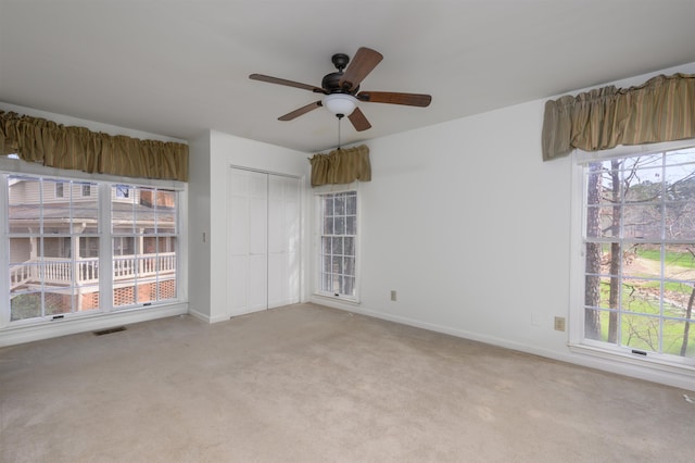 unfurnished bedroom with baseboards, multiple windows, a closet, and light colored carpet