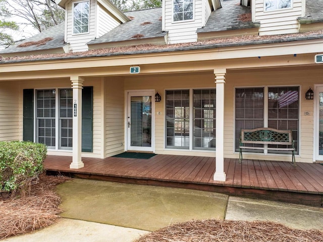 property entrance with covered porch and a shingled roof