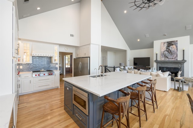 261 Reynolds Dr, Eatonton, GA 31024 - kitchen with a sink, appliances with stainless steel finishes, high vaulted ceiling, white cabinets, and a kitchen breakfast bar