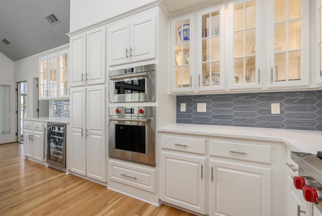 261 Reynolds Dr, Eatonton, GA 31024 - kitchen with beverage cooler, decorative backsplash, light countertops, white cabinets, and vaulted ceiling